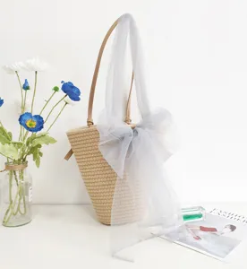 Geflochtene Strohtasche mit großer grauer Netzschleife und braunen Griffen für den Sommer.