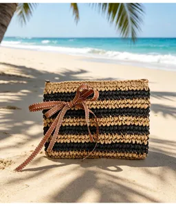 Detailansicht der handgefertigten Stroh Clutch mit schwarz-beigen Streifen und brauner Schleife.