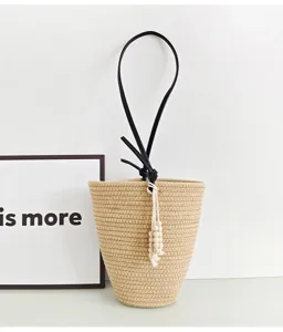 Nahaufnahme der Stroh-Eimer-Tasche mit schwarzem Lederriemen und hübschen Holzperlen.