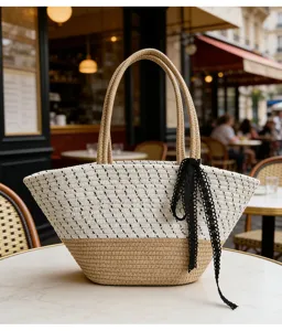 Nahaufnahme der gewebten Strohtasche mit schwarzer Spitzenschleife im europäischen Café-Stil.