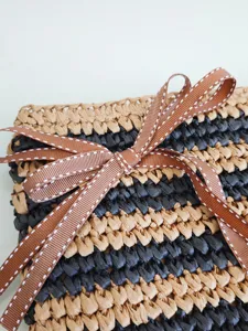 Handgefertigte Bast-Clutch Tasche mit stilvollem Streifenmuster und eleganter brauner Schleife.