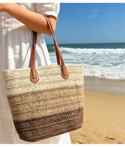 Nahaufnahme der gewebten Strohtasche mit schickem Farbverlauf und braunen Ledergriffen.
