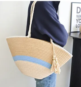 Nahaufnahme Detail der gewebten Strandtasche mit blauem Streifen und Quasten Anhänger.