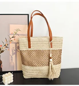 Detailansicht der Strohtasche mit durchbrochenem Design, Kontrastfarben und Quastenanhänger.