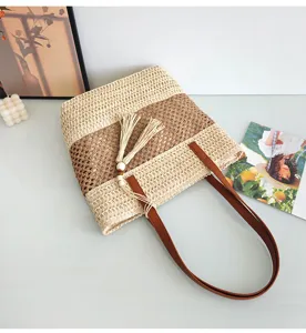 Nahaufnahme der gewebten Strohtasche mit kontrastierendem Farbdesign und Quasten.