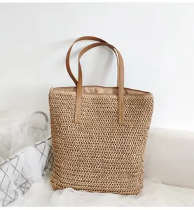 Detailansicht der gewebten Stroh-Tragetasche mit braunen Ledergriffen, ideal für den Strandurlaub.