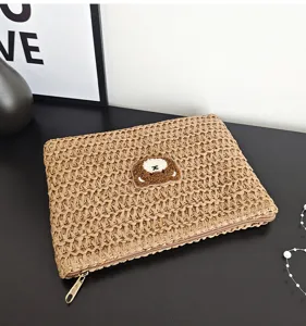 Sac pochette en paille tressée avec un joli patch d'ours brodé, idéal pour les vacances d'été.