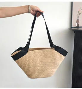 Detailansicht der beigen geflochtenen Strohtasche mit schwarzen Trägern für den Alltag.