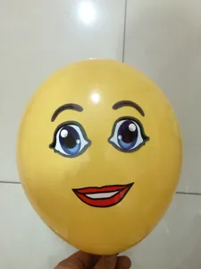 Yellow balloon with funny cartoon face sticker, close-up view showing cute eyes and red lips.