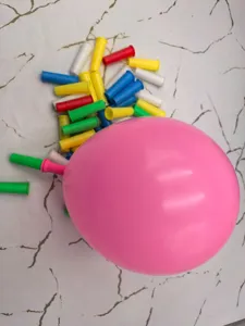 Detailansicht eines rosa Ballons und bunter Plastikmundstücke für das Lungentraining.
