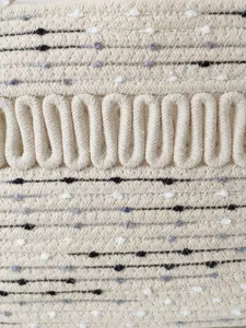 Nahaufnahme einer beige geflochtenen Baumwoll-Strandtasche mit hohlem Schlaufendesign.