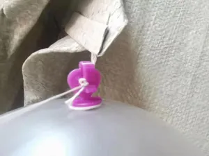 Vue de détail du crochet pour ballon violet, montrant sa ficelle et sa base adhésive.