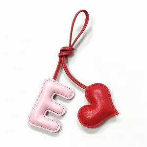 Detailed close-up shot of the pink leather letter E and red heart bag charm pendant.