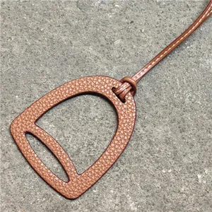 Nahaufnahme eines braunen PU Leder Steigbügel Taschenanhängers mit Ziernähten.