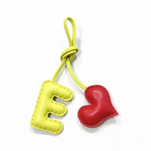 Handmade leather letter E and red heart bag charm detail, exquisite stitching pendant for bags.