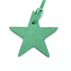 Gros plan détaillé d'un charm de sac en cuir vert en forme d'étoile avec sa lanière assortie.