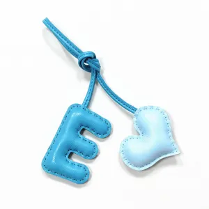 Handmade blue leather letter E and heart bag charm detail shot, keychain pendant.