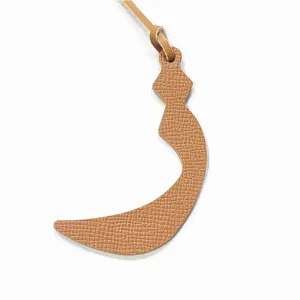 Detailed close-up of textured leather crescent bag charm with matching strap accessory.