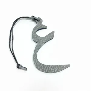 Grey leather Arabic letter bag charm with black strap, stylish mini purse accessory for women.