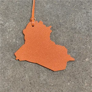 Leather map bag charm detail shot showing orange texture and hanging strap close up.
