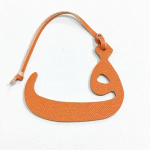 Primer plano detallado de colgante de bolso de cuero naranja con letra árabe accesorio.