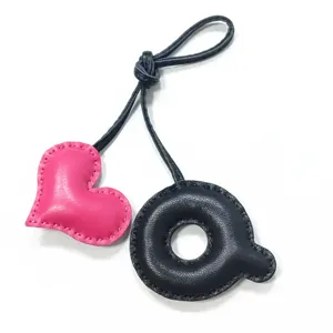 Nahaufnahme Detail einer handgefertigten schwarzen Leder Buchstabe Q und rosa Herz Tasche.