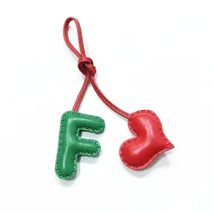 Detailaufnahme des Leder Buchstaben F und Herz Taschenanhängers mit Handnaht für Damentaschen.