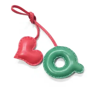 Handgemachter Leder-Taschenanhänger mit rotem Herz und grünem Buchstaben Q Motiv.
