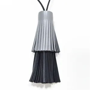 Detailansicht eines zweifarbigen Leder-Quasten-Taschenanhängers in Grau Schwarz mit langer Kordel.