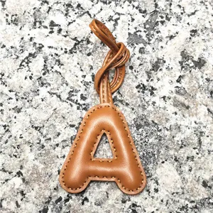 Close-up detail of the light brown leather alphabet letter charm, fine stitching craftsmanship.