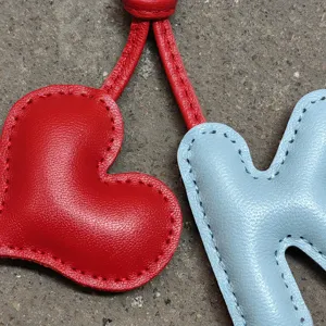 Leder Buchstabe Taschenanhänger und süßes Herz Detail, stilvolles Accessoire für Damentaschen.