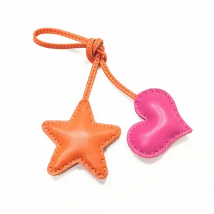 Pendentif de sac artisanal en cuir en forme d'étoile et de cœur avec coutures contrastées.