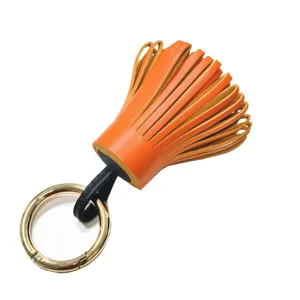 Schicker orangefarbener Leder-Quasten-Taschenanhänger mit goldener Hardware.