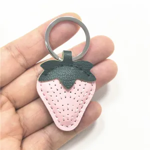 Pink leather strawberry keychain detail, cute bag charm pendant and car key holder ornament.
