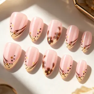 Vue detaillee d'ongles artificiels rose nude avec des motifs floraux marron et pois dores.