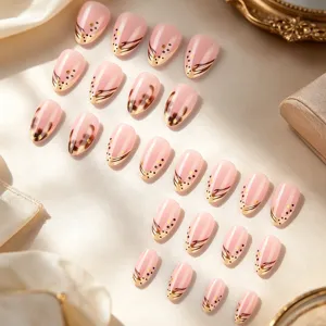 Détail de faux ongles nude rose avec style français et motif de pois dorés élégants.