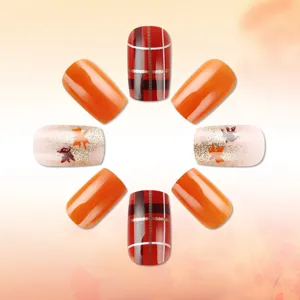 Detailed view of autumn press-on nails featuring autumn maple leaf and festive plaid patterns.