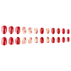Detail view of short almond press-on nails with red glossy finish and gold glitter leaves.