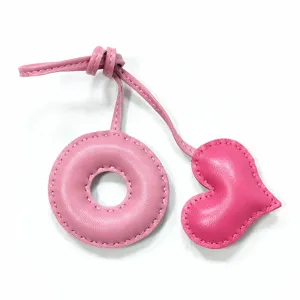 Pink leather donut and heart charm close-up, handmade stitch bag pendant accessory details.