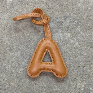 Gros plan détaillé du charm de sac lettre A en cuir marron avec une lanière élégante.