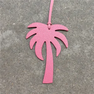 Pink leather palm tree bag charm detail, stylish purse accessory and car pendant decor.
