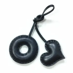 Black leather donut and heart bag charm with handmade stitching, perfect stylish accessory.