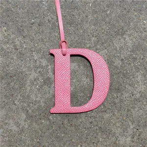 Pink leather letter D bag charm detail shot, elegant handbag accessory with strap ornament.