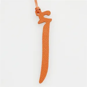 Detailed close-up view of the orange leather Arabic letter bag charm with matching cord.