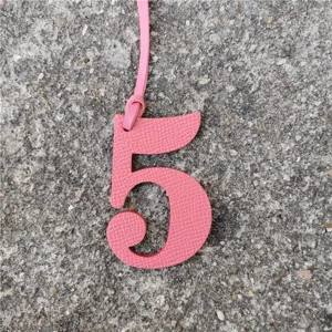 Gros plan détail pendentif chiffre 5 en cuir rose, accessoire sac DIY mignon et chic.