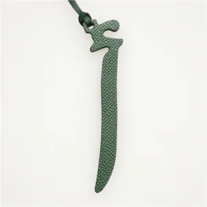 Arabic letter leather bag charm detail, dark green textured leather keychain accessory ornament.