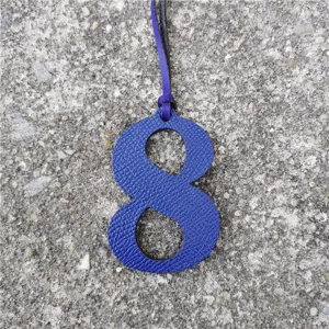 Close-up detail of the blue leather number 8 bag charm pendant with fine hanging strap.