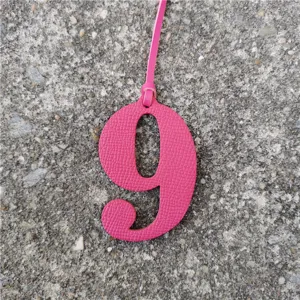 Close-up detail of hot pink leather number 9 bag charm, stylish handbag pendant accessory.