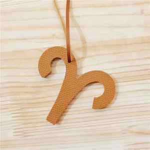 Gros plan sur un charm de sac zodiaque Bélier en cuir texturé marron avec lanière suspendue.
