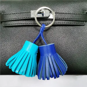 Dual-color leather tassel bag charm detail showing vibrant blue and cyan fringes with metal ring.